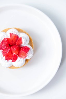 Beyaz tabakta çilekli peynirli tart.