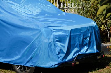 A vibrant blue car cover protecting a vehicle outdoors