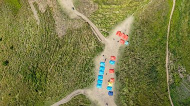 Holbung Tepesi, Toba Gölü 'nün çimenli sırtlarındaki renkli kamp çadırlarının hava manzarası.