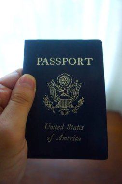 Elde tutulan bir Amerikan pasaportu yasal ikamet ve Amerikan vatandaşlığını gösteriyor. Yakın plan, belgenin kapağını ve özgünlüğünü vurgular.