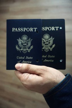 Elde tutulan bir Amerikan pasaportu yasal ikamet ve Amerikan vatandaşlığını gösteriyor. Yakın plan, belgenin kapağını ve özgünlüğünü vurgular.