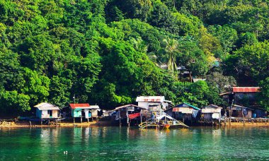 Palawan 'da deniz aşırı bungalovları olan güzel bir plaj manzarası, kristal berrak, şeffaf su. Arka plandaki yemyeşil orman tropikal, pitoresk bir manzara yaratır..