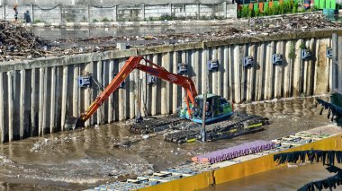 Kazıcı gün boyunca nehri çöpten temizler. ortam