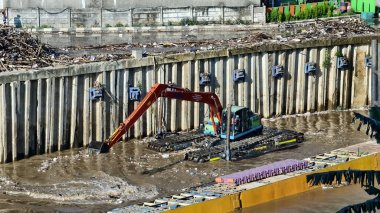 Kazıcı gün boyunca nehri çöpten temizler. ortam
