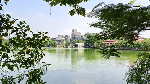 modern building with unique architectural design beside a lake with blue sky, with reflection in the water. the central library of the university of indonesia