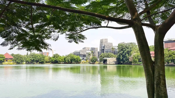modern building with unique architectural design beside a lake with blue sky, with reflection in the water. the central library of the university of indonesia