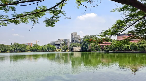 modern building with unique architectural design beside a lake with blue sky, with reflection in the water. the central library of the university of indonesia