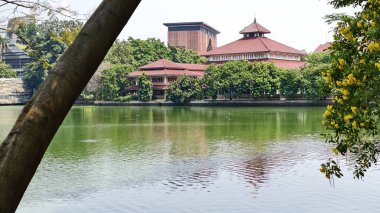 reflection of prism building on Lake.trees as foreground and blue sky