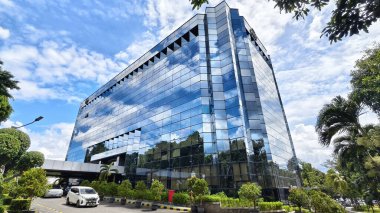 Güzel mavi gökyüzü ve beyaz bulutları olan ofis binası. Düşük açılı gökdelen görünümü