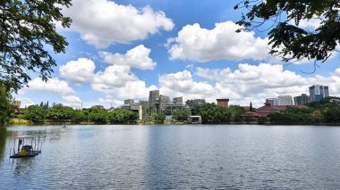 modern building with unique architectural design beside a lake with blue sky, with reflection in the water. the central library of the university of indonesia