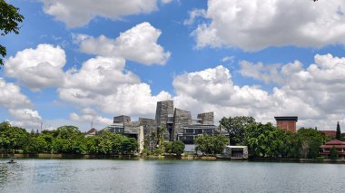 modern building with unique architectural design beside a lake with blue sky, with reflection in the water. the central library of the university of indonesia
