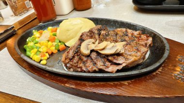 Bir tabak ızgara biftek, yanında da meze ile birlikte muhtemelen yumuşak bir biftek dilimi. Mantar, patates püresi ve sebze.