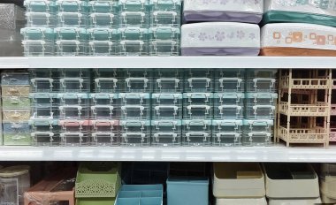 Renkli plastik depolama kutularının, sepetlerin ve kutunun ön görüntüsü bir raf ünitesinde düzgünce düzenlenmiştir.