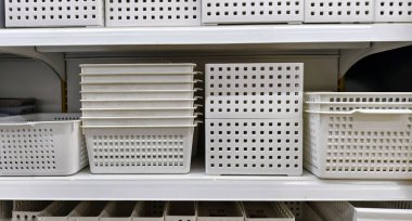 Plastik beyaz depolama kutuları, sepetler ve kutular raflarda düzgün bir şekilde düzenlenmiştir.