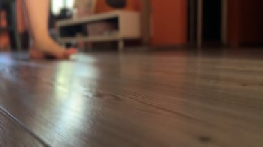 Çıplak ayaklı birinin kameraya doğru yürüdüğü yakın plan. Sadece bacakların ve ayakların alt kısmı görülebilir. Basit, doğal ve sakin bir ev anı..