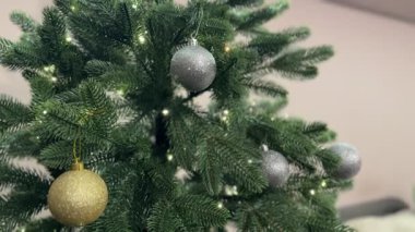 Bir çift Noel ağacını süs ve ışıklarla süslüyor. Video şenlik havasını ve neşeli tatil hazırlıklarını yakalıyor..