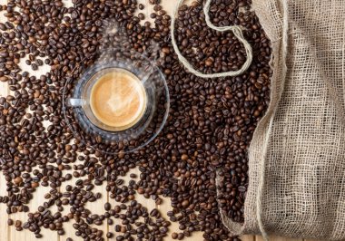 Ahşap masa kahve çekirdekleri tam üzerinde sıcak Espresso fincan.