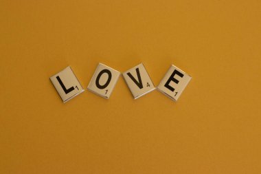 Aşk kelimesi, turuncu arka plandaki masa oyunu harflerinden yapılmıştır. Yüksek kalite fotoğraf