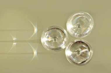 Üç su bardağı, minimalist arkaplanda ışık kırılması etkisi. Yüksek kalite fotoğraf