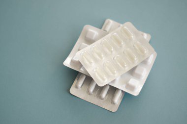 Haplar ve kapsüller mavi minimalist bir arka plana yerleştirilmiş. Yüksek kalite fotoğraf