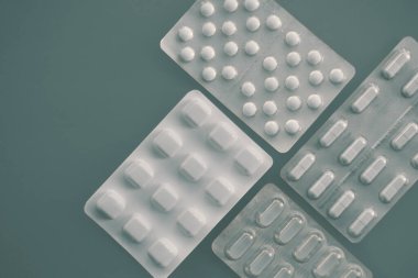 İlaç ambalajlarındaki haplar ve kapsüller en az gri-yeşil arkaplanda düzenlenmiştir. Yüksek kalite fotoğraf