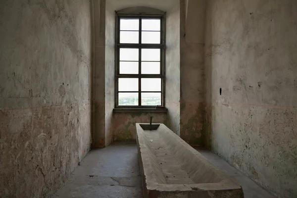 Ventana detrás de un abrevadero de piedra en una antigua habitación estrecha — Foto de Stock