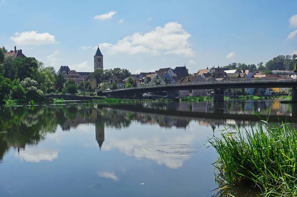 都市の背景と川の上の橋 ドイツのシュヴァンドルフ レーゲンスブルクからドナウ川沿いの道 街の建物や塔は川に反映され 白い雲と青い空が上にあります — ストック写真