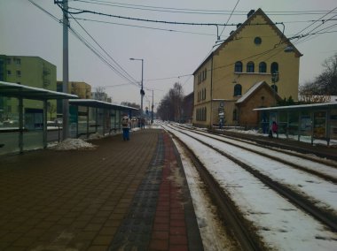 Budapeşte istasyonundaki karla kaplı tramvay raylarına geniş bir perspektif. Sarı şehir mimarisi ve hafif sabah karı klasik bir Orta Avrupa kış ulaşım ve seyahat teması oluşturur.