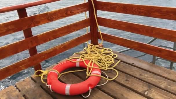 Спасательное оборудование - Красный спасательный буй с веревкой на синем фоне морской воды. — стоковое видео