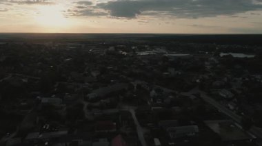 İnsansız hava aracı, yeşil ağaçları ve günbatımı gökyüzü olan bir köyde dosdoğru uçuyor..