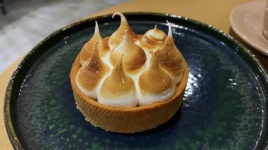 Koyu bir tabakta altın kabuklu ve kremalı lezzetli bir turtanın yakın görüntüsü. Yemek fotoğrafçılığı, kafe menüsü, fırın promosyonu veya tatlı yaşam tarzı kavramları için mükemmel..