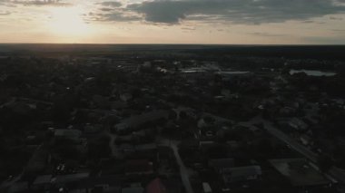 İnsansız hava aracı, yeşil ağaçları ve günbatımı gökyüzü olan bir köyde dosdoğru uçuyor..