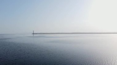 Parlak güneş ışığı altında sakin bir denizde deniz feneri. Kıyı şeridi ve ufkun havadan görüntüsü. 