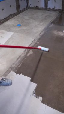 Tadilat ve mühürleme için beton zemine şeffaf epoksi reçinesi sürüyorum. Endüstriyel kat onarımı ve bakımı. İnşaat teması, dikey yavaş çekim videosu