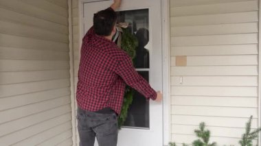 Adam tatil geleneğinin bir parçası olarak kapısına Noel çelengi koyar. Sıcaklığın, evin ve kış mevsiminin neşeli ruhunun sembolü..