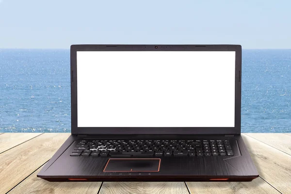 Black laptop over a table in the beach as concept for teleworking, telework ,telecommuting