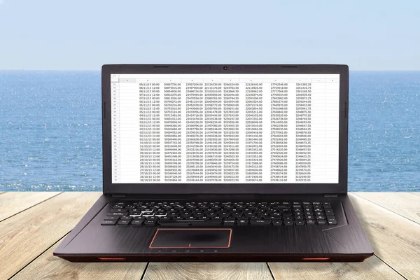 Black laptop over a table in the beach as concept for teleworking, telework ,telecommuting