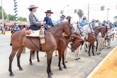 Seville, İspanya - 5 Mayıs 2019: Ata binen ve Seville 'deki Nisan Fuarı' nı (Feria de Sevilla) kutlayan güzel kadınlar. Seville Nisan Fuarı 5 Mayıs 2019, Sevilla, İspanya