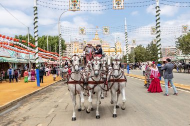 Seville, İspanya - 5 Mayıs 2019: İnsanlar Seville, İspanya 'da 5 Mayıs 2019 tarihinde Sevilla Panayırı' nın ana kapısından Nisan Fuarı 'na at arabasıyla girdiler.