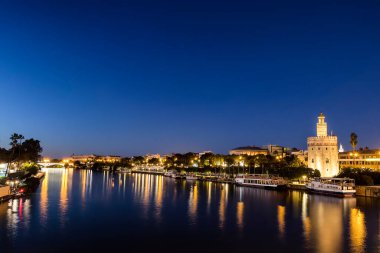 Guadalquivir Nehri 'nin diğer yakasından gün batımında, Seville (Endülüs), İspanya' da uzun süre Altın Kule (Torre del Oro) görülür..