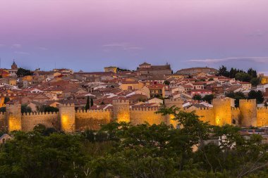 Ortaçağ 'ın Avila şehrinin duvarları gün batımında ışıklar açık, İspanya