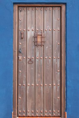 Mavi duvarın üzerindeki eski kahverengi ahşap giriş kapısı.