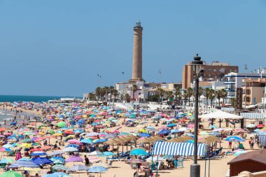 Chipiona, Cadiz, İspanya - 13 Haziran 2021: Güneşli bir günün keyfini çıkaran şemsiyeli Chipiona plajı