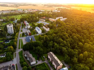 Vinni, Estonya - 10 Ağustos 2025: Vinni 'nin altın saatindeki hava manzarası. Modern apartmanlar, evler ve Vinni anaokulu güneşli bir yaz akşamında yemyeşil orman ve tarlalarla çevrili..