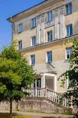 Sillamae, Estonya - 13 Temmuz 2025: Süslü sütunları ve parlak yaz güneşi ışığı altında klasik cepheli tarihi Stalinist mimari binası. Yeşil ağaçlar girişi beyaz balyoz ile çevrelemişler..