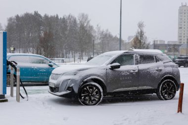 Vilnius, Litvanya - 26 Kasım 2025: Şiddetli kar yağışı sırasında EV istasyonunda çalışan elektrikli SPARK araba paylaşım araçları. Sert havada modern hareketlilik