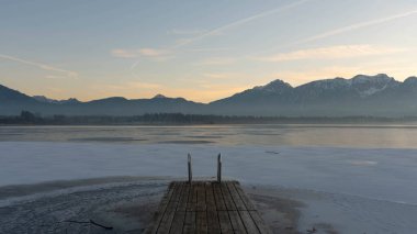 2025 kışında Bavyera 'da Hopfen Gölü' nde günbatımı - Büyük Işık ve Buz ile güzel Alpler. Yüksek kalite fotoğraf