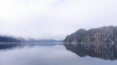 Bavyera 'daki Alpsee' nin üzerinde muhteşem Mavi ve Mor Işıklı Güzel Manzara - Moody Kış Manzarası 'nda Göl Resmi. Sisli bir gün ve çok kaliteli bir fotoğraf.