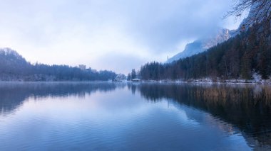 Bavyera 'daki Alpsee' nin üzerinde muhteşem Mavi ve Mor Işıklı Güzel Manzara - Moody Kış Manzarası 'nda Göl Resmi. Sisli bir gün ve çok kaliteli bir fotoğraf.