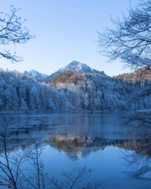 Almanya 'nın Bavyera Allgaeu bölgesindeki Alatsee' de güneşli kış atmosferiyle donuk dağlar yansıyor. Yüksek kalite fotoğraf